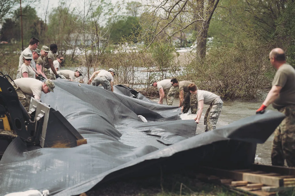 Crew laying large flood barrier sheeting