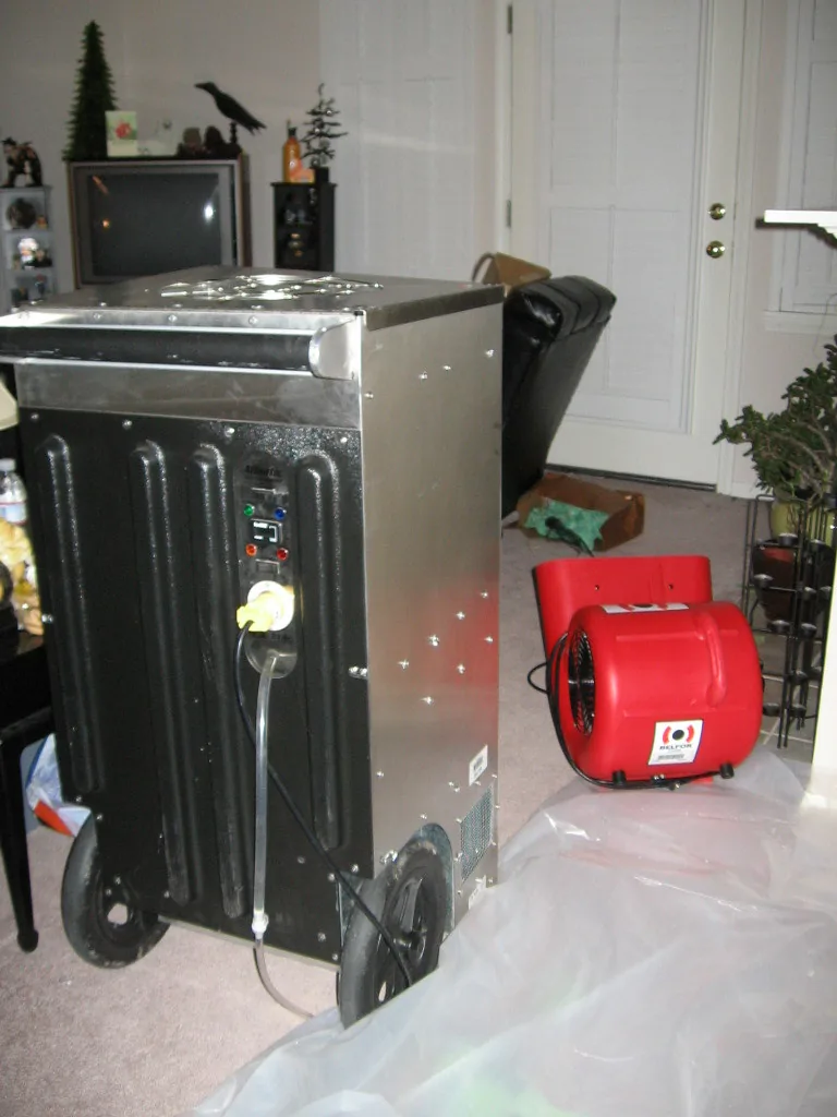 Dehumidifier and red air mover operating in a room