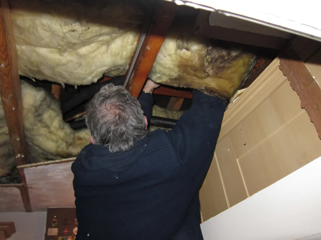 Worker repairing pipes in an open ceiling
